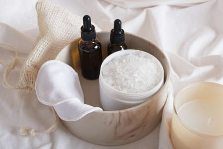 reusable cotton pads, aroma oil or serum, bath salt and aroma candle on a white sheet, eco friendly spa conceptの写真素材
