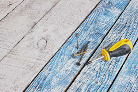 self-tapping screw and screwdriver on wooden board background copy spaceの写真素材