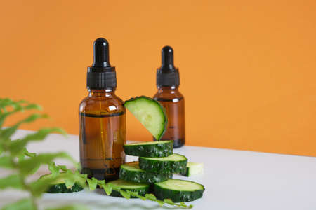 fern leaves, cucumber slices and brown glass dropper bottles on gray and brown background, natural cosmetics concept, body and face skin care, serum or cosmetic oil in a bottle with a dropperの写真素材