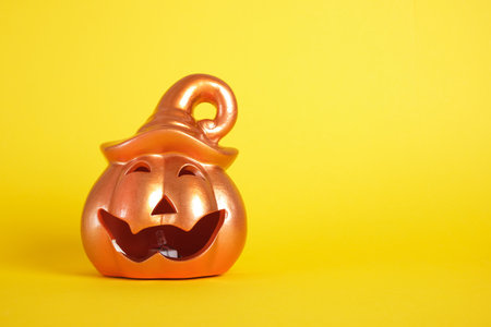 A ceramic halloween jack o lantern pumpkin on yellow backgroundの写真素材