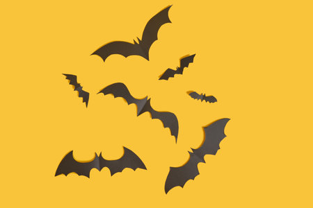 bats cut from black paper on orange background handmade halloween decor, top view copy spaceの写真素材