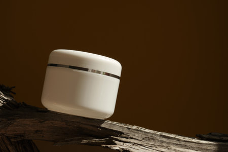 white cosmetic jar with cream on a log and with hard shadows in the background. The concept of a beauty salon and natural cosmetics.の写真素材