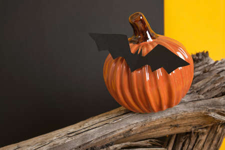 close-up of ceramic decorative halloween pumpkin on wooden timber on yellow and black background...