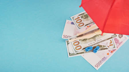 doll on money like on beach towels under a red umbrella, expensive beach vacation concept copy spaceの写真素材