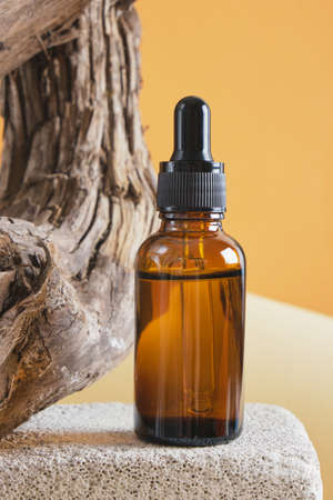 brown glass bottle with a pipette on a concrete podium on a wooden driftwood background, brown background copy space natural cosmetic conceptの写真素材