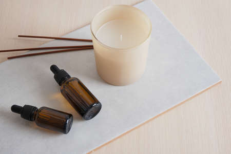 aroma sticks, brown glass bottle with pipette and aroma candle on ceramic tile, serum or oil natural...