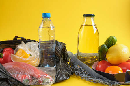 plastic disposable packaging versus reusable, no plastic concept, net bag and plastic grocery bag on yellow background copy spaceの写真素材
