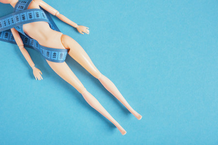 the doll is wrapped with a measuring tape, the cult of slimness and anorexia concept, diet and loss...