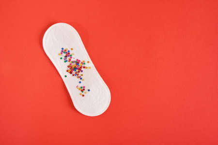 daily sanitary napkin and stars confetti on red background copy spaceの写真素材