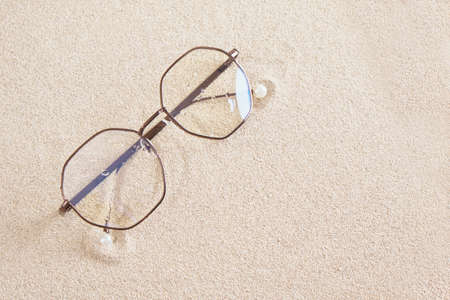 stylish eye glasses in a round metal frame on the sand copy space top viewの写真素材