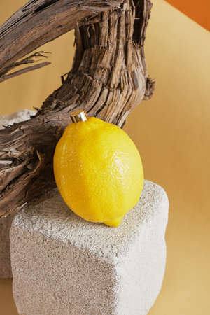 perfume with lemon scent concept, lemon with a spray of perfume on a concrete podium against a background of driftwoodの写真素材
