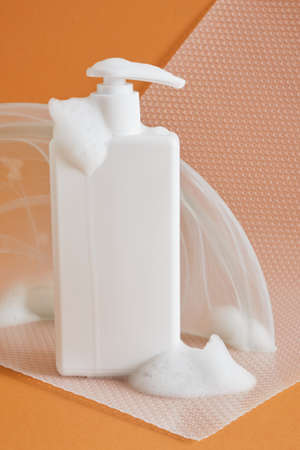 White soap and cream container on brown background. Packaging of cream, lotion, gel, facial foam or...