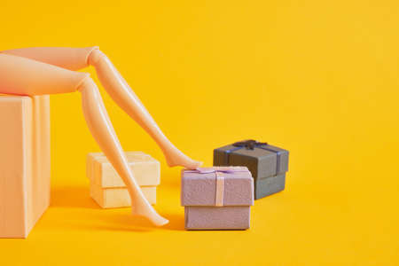 doll legs and gift boxes on yellow background, lots of doll legs, shoe store and sales season copy...