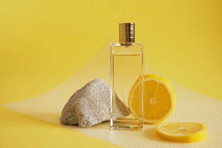 citrus scent, perfume with lemon scent concept, concrete block fragment, lemon slice and bottle of perfume on yellow backgroundの写真素材