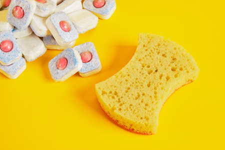 dishwasher tablets and dishwashing sponge on yellow background, dishwashing products, hand wash...