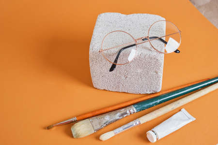 eye glasses on concrete block brown background, artist workshop concept tube of paint and brushesの写真素材