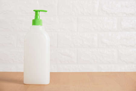 plastic blank bottle with dispenser for soap or dishwashing detergent on table against white brick wall background mock upの写真素材