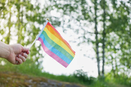 flag symbol of the lgbt community on a background of grass and trees, flag in woman's handの写真素材