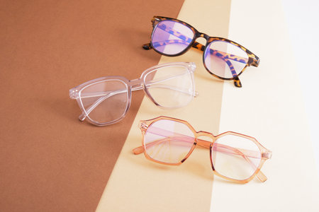 several pairs of eye glasses on a geometric background of different shades of brownの写真素材