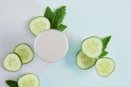mock up blank jar with a cosmetic medium and pieces of cucumber, aluminum jar with skin care cream with cucumber extract, gray-blue background copy space top viewの写真素材