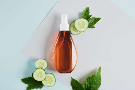 mock up blank spray bottles and cucumber slices, dark brown plastic bottle with a cosmetic product for body or hair care with cucumber extract, gray-blue background copy space top viewの写真素材