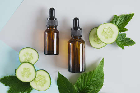 mock up blank amber glass bottle with pipettes and cucumber slices, dark brown dropper bottle with cosmetic productの写真素材