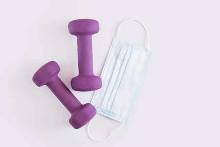 two dumbbells and medical mask on gray background fitness during coronavirus pandemic top view copy spaceの写真素材