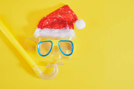 diving set, santa claus hat, sun cream and a bottle of lemonade on a yellow background, Christmas holidays on the beach in a warm countryの写真素材