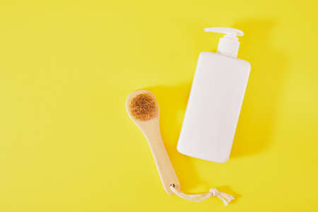 cream bottle and massage brush on a green background. face massage and body care concept. top view copy spaceの写真素材