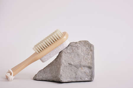 wooden natural brush for pedicure on a stone stand on a gray background, massage with a brush and...