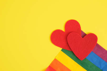 two felt hearts ans lgbt rainbow colors flag on yellow background, free love and pride conceptの写真素材