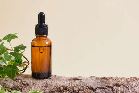 Amber glass Bottle with face serum or oil on tree bark on beige background. natural cosmetic conceptの写真素材