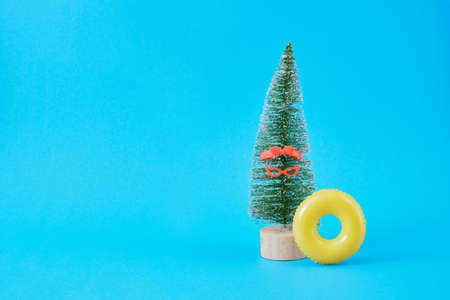 toy decorative Christmas tree and an inflatable circle on a blue background. vacation on the beach for a winter vacationの写真素材