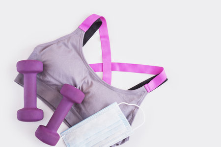 sports bra, medical face mask and two dumbbells on a gray background fitnessの写真素材