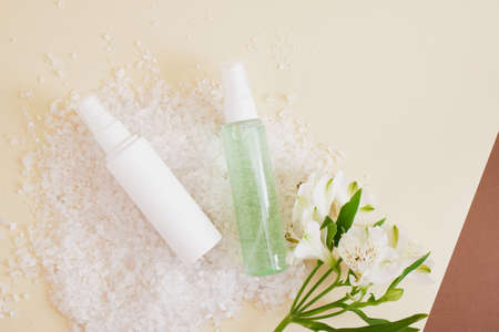 lily flowers, two mock up cosmetic bottles with cream and gel for skin care on the background of sea salt, spa conceptの写真素材
