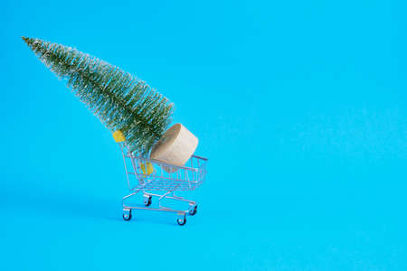 Shopping cart with fir tree on blue background. Christmas and New year sale concept copy spaceの写真素材