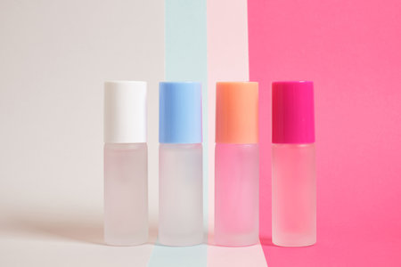 several bottles of perfume of different colors on a bright multicolored background, mock up perfume bottles on a striped background, copy space, cosmetics backgroundの写真素材