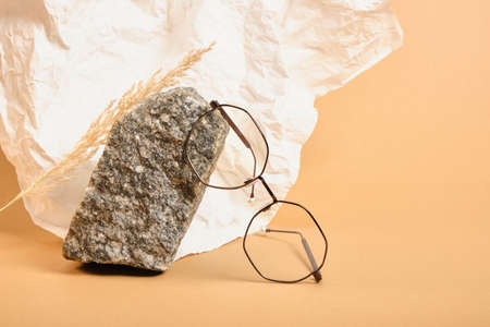 stylish glasses on a stone on a background of crumpled white paper, trendy still life, accessories for vision correction close upの写真素材