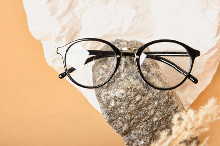 stylish glasses on a stone on a background of crumpled white paper, trendy still life, accessories for vision correction close upの写真素材
