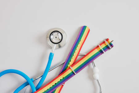 medical stethoscope and two bracelets lgbt pride flag on gray background copy space, gay medical careの写真素材
