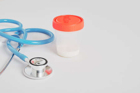 medical stethoscope and donor sperm jar on gray background, sperm and egg donation, artificial insemination, surrogacyの写真素材
