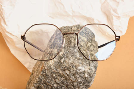 stylish glasses on a stone on a background of crumpled white paper, trendy still life, accessories for vision correction close upの写真素材