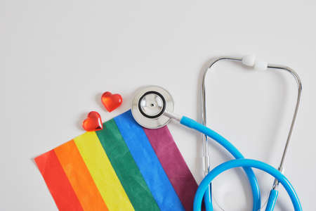 medical stethoscope, little red hearts and lgbtq community flag on gray background copy space, individual approach in medicine concept, unconventional love and artificial inseminationの写真素材