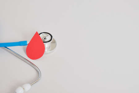 Drop of blood and stethoscope on a gray background. World Blood Donor Day. World Hemophilia Day. World Diabetes Day. Blood donation concept. Copy space.の写真素材