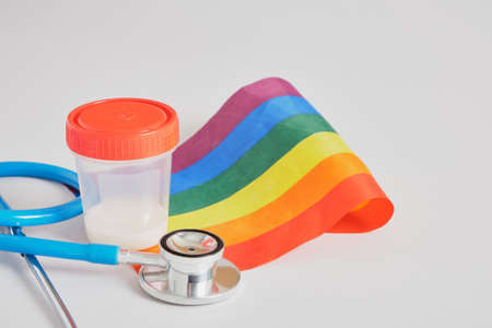 medical stethoscope, lgbt pride flag and a jar of donor sperm on a gray background copy space, sperm donation, artificial fertilization concept, surrogacy for a gay coupleの写真素材