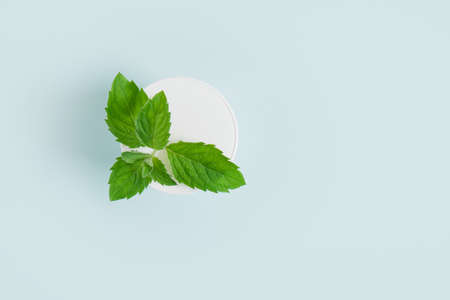 cosmetic white cream jar and fresh mint on light blue background. Organic cosmetics concept. Natural cosmetic product concept. Organic skin care productの写真素材