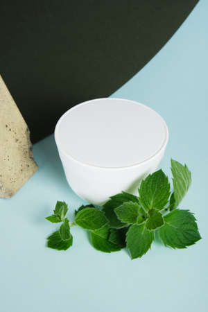 stone, cosmetic cream jar and fresh mint on green and blue background. Organic cosmetics concept. Cosmetic container mockup without label Natural skincare product.の写真素材