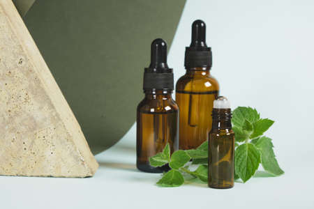 stone, amber glass dropper bottles and mint leaves, peppermint oil in a bottle with pipette, the use of peppermint oil in aromatherapy and cosmeticsの写真素材