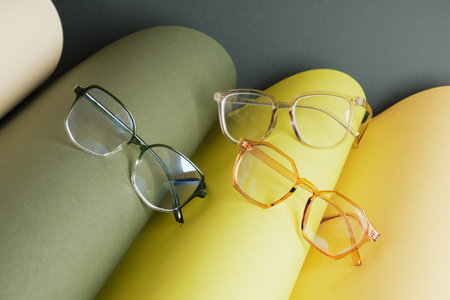 some different glasses on rolled paper, geometric background, green colors, dark green background, vision test concept, beautiful stylish fashion accessories in optics storeの写真素材