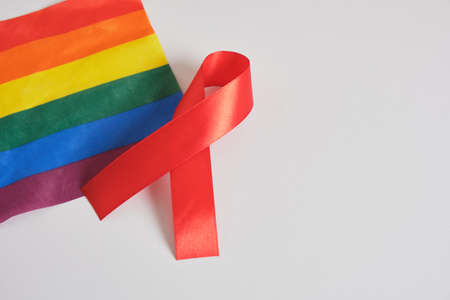 Stop AIDS, HIV concept. Red ribbon against on flag of LGBT pride gray background